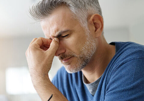 Man with headache holding bridge of nose