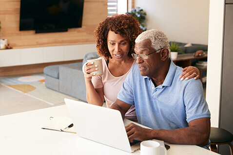 Mature couple at kitchen counter with laptop